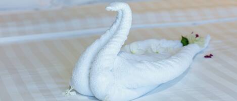 Una toalla con forma de cisne sobre una cama con colcha a cuadros.