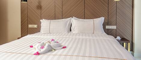 A neatly made bed with white linens and pink flowers, a wooden headboard, and two bedside lamps.