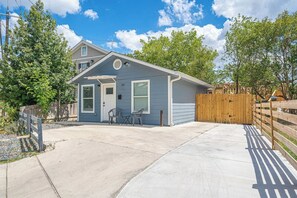 A single-story house with a garage, a front door, and a small patio area with two chairs. - Downtown 2 Bedrooms. Walk to Cnvntn Ctr. Pets ok (San Antonio)