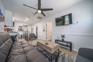 A modern living room with a sofa, a coffee table, a TV, and a kitchen in the background. - Downtown 2 Bedrooms. Walk to Cnvntn Ctr. Pets ok (San Antonio)