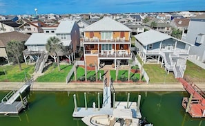 Uma propriedade à beira-mar com um cais, um barco e uma casa grande com varanda com vista para a água.