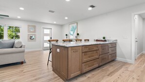 Une cuisine spacieuse avec des meubles en bois, un plan de travail en marbre et un grand îlot central.