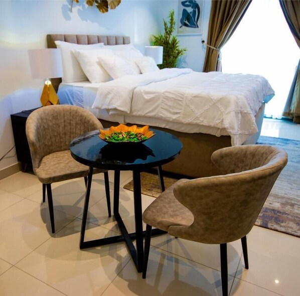 Habitación de hotel con cama, dos sillones, una mesita con frutero y una planta en maceta.