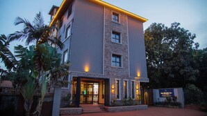 Un hotel de varios pisos con fachada de piedra, ventanas amplias y una entrada bien iluminada.
