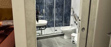 A modern bathroom with a glass-enclosed shower, a white sink, and a bidet.