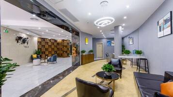 A modern lobby with a reception desk, seating area, and a staircase.
