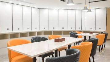 Una sala conferenze moderna con un tavolo bianco, sedie nere e arancioni, e luci a sospensione.