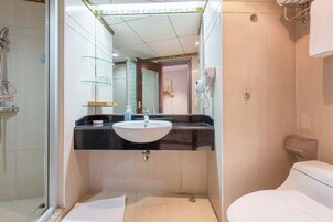 Un baño moderno con cabina de ducha de vidrio, lavamanos con encimera negra y inodoro blanco.