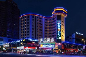 A multi-story hotel with a prominent sign at the entrance, multiple floors, and a curved facade.
