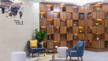 A lobby with a wooden bookshelf, seating area, and a world map on the wall.