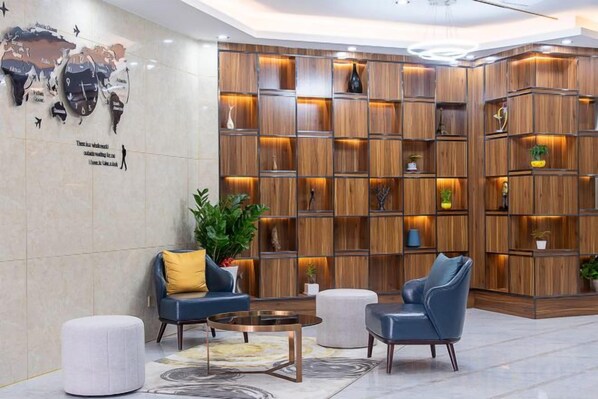 A lobby with a wooden bookshelf, seating area, and a world map on the wall.