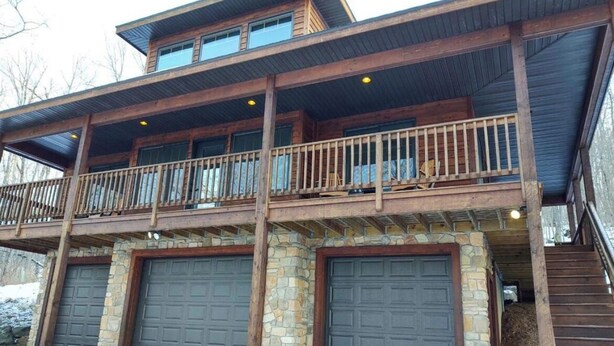 Un bâtiment à deux étages doté d’un balcon, de fondations en pierre et de deux portes de garage.