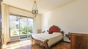A bedroom with a wooden bed, a chandelier, and a view through a sliding glass door. - Detached villa with pool and garden in the Ligurian countryside (Gattorna)