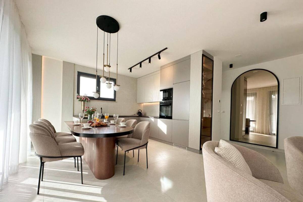 A modern dining area with a round table, chairs, and a pendant light.