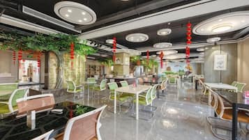A modern dining area with round tables, green chairs, and a polished floor.