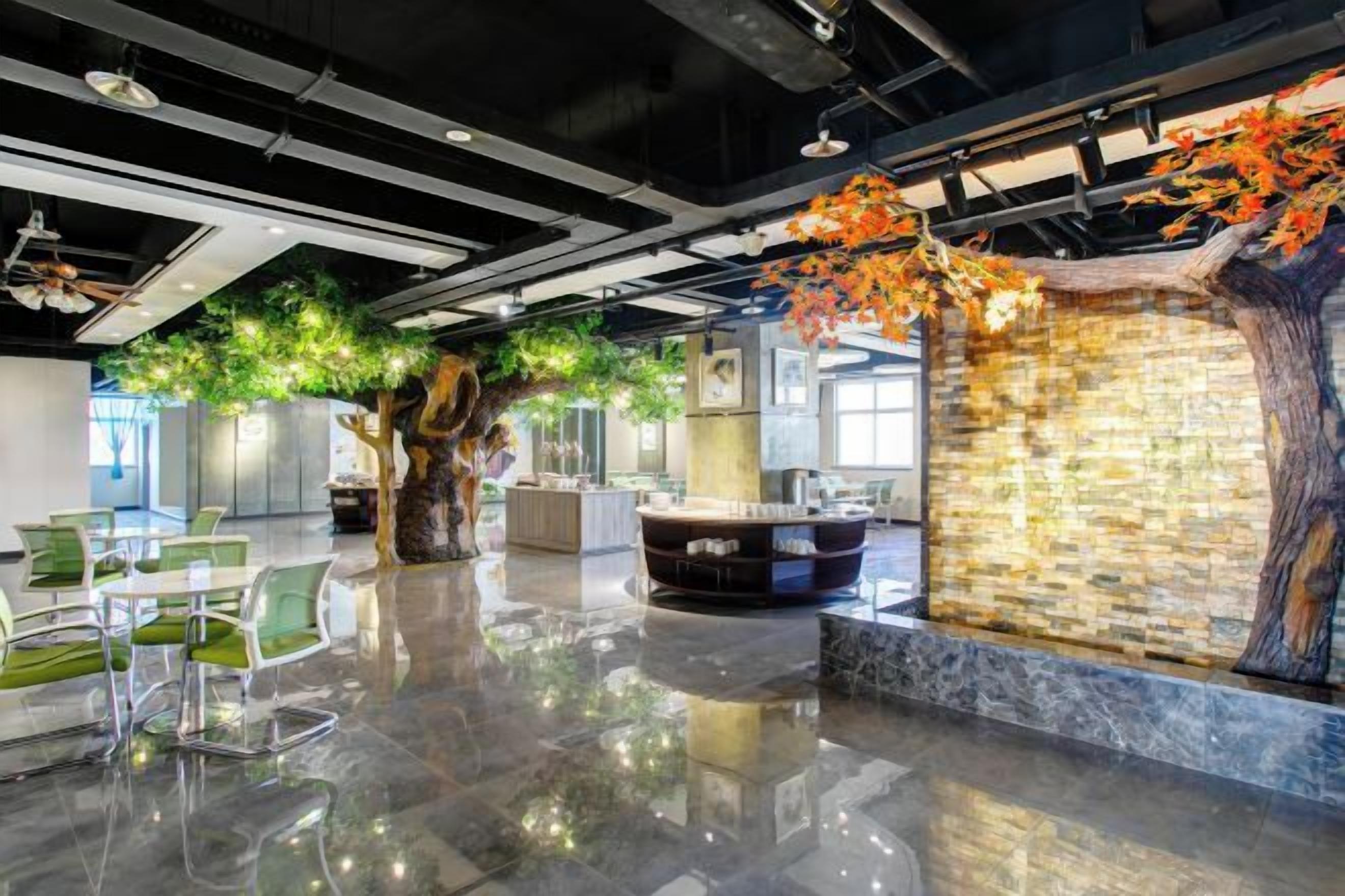 A modern interior with a reflective floor, a seating area, and a decorative tree with green foliage.