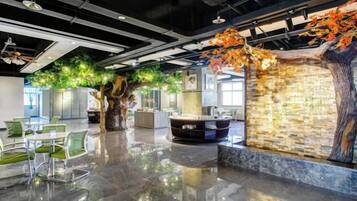 A modern interior with a reflective floor, a seating area, and a decorative tree with green foliage.