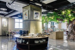 Una cafetería moderna con mostrador central, zona de mesas y una gran decoración de árbol.