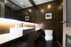 Un baño moderno con un espejo grande, lavabo blanco y retrete.
