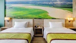 A hotel room with two beds, a mural of a river landscape, wooden headboards, and bedside lamps. - Yuncheng Juhetai Hotel (Yanhu South Wind Square) (Yuncheng)