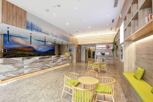 A hotel lobby with a reception desk, seating area, and a large TV screen.