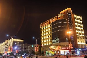 Un hotel moderno con varios pisos, amplias ventanas y una entrada destacada con señalización iluminada.