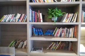Una estantería con varias repisas que contiene libros y una planta en maceta.