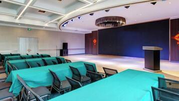 A conference room with rows of tables, a stage, and a podium.
