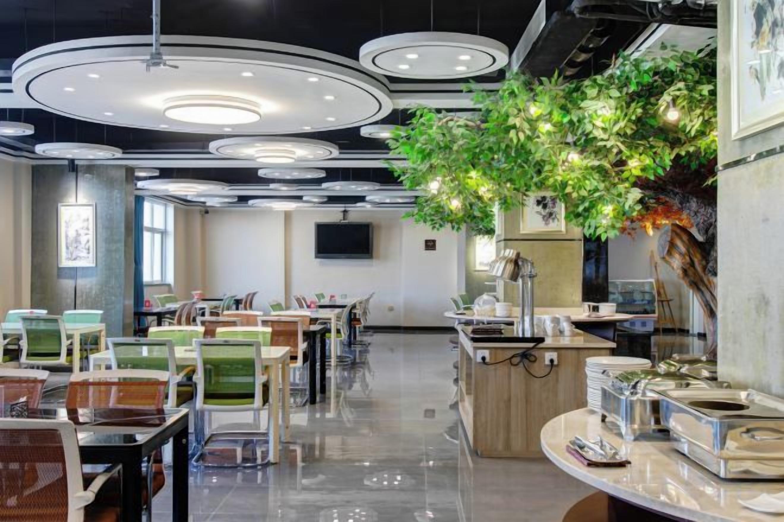 A modern dining area with multiple tables and chairs, a central counter, and a ceiling with circular light fixtures.