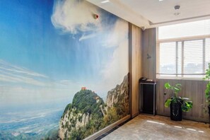 A room with a mural of a mountain landscape, a window with blinds, and a potted plant. - Yuncheng Juhetai Hotel (Yanhu South Wind Square) (Yuncheng)