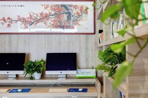 A reception desk with two monitors, a plant, and a framed artwork. - Yuncheng Juhetai Hotel (Yanhu South Wind Square) (Yuncheng)