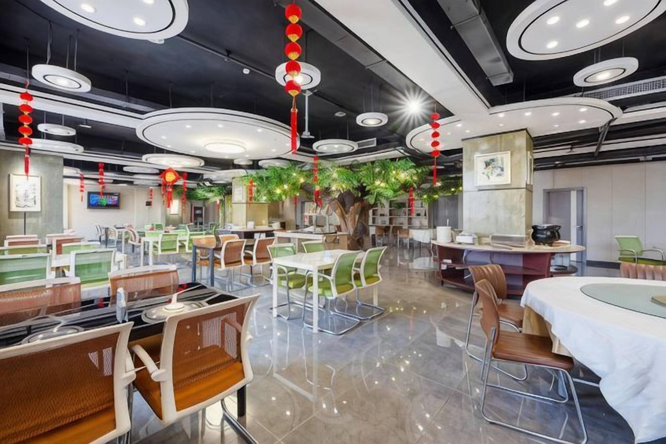 A restaurant with multiple dining areas, including booths and tables, with a modern ceiling design and red lanterns.