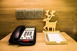 Ein Holztisch mit Telefon, einem Hirsch aus Holz als Dekoration und einem Stifteständer.