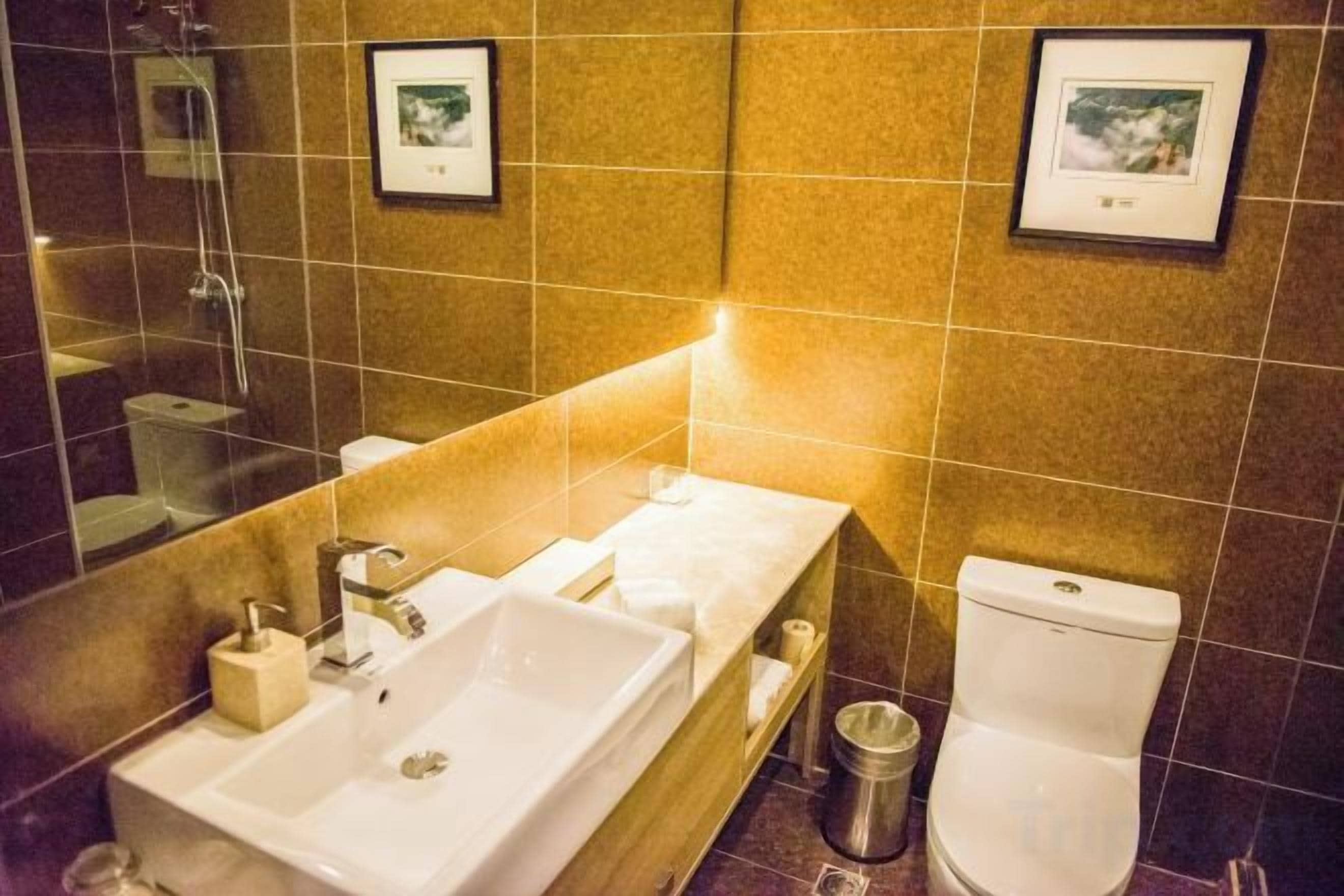 Et badeværelse med vask, toilet og spejl.