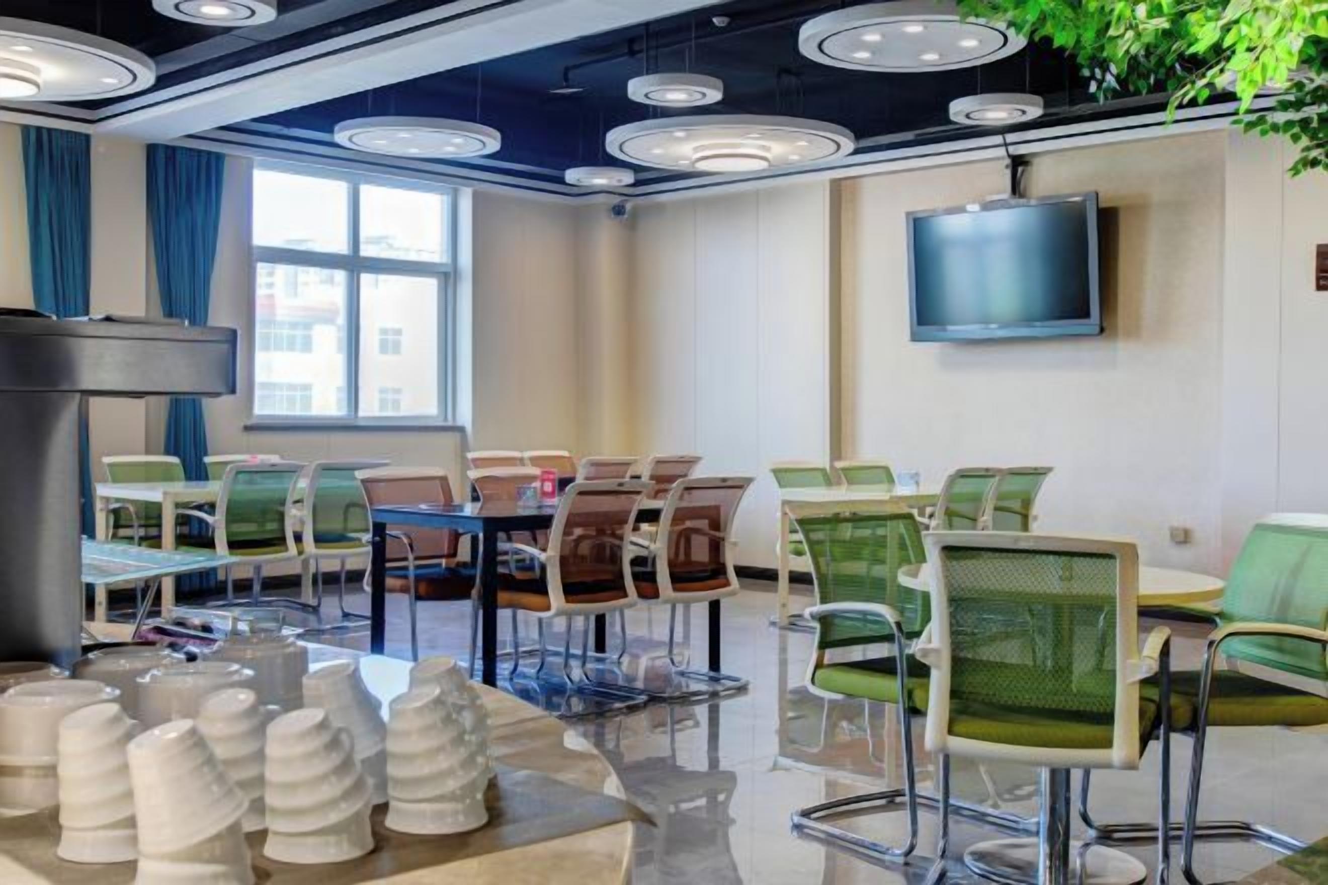 A conference room with a large table, chairs, a television, and a plant.