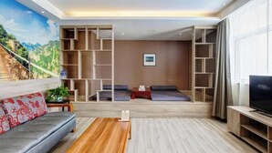A modern living room with a sofa, coffee table, TV, and built-in shelving. - Yuncheng Juhetai Hotel (Yanhu South Wind Square) (Yuncheng)