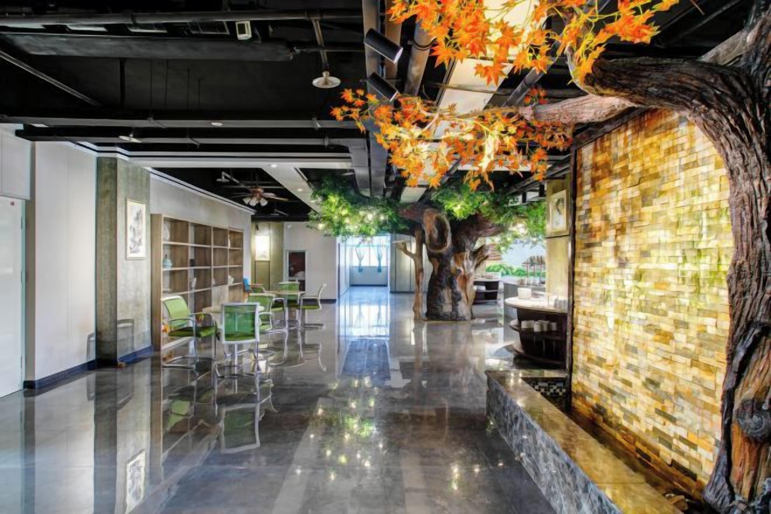 A modern interior with a polished floor, a large tree sculpture, and a wall with a mosaic pattern.