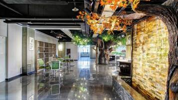 A modern interior with a polished floor, a large tree sculpture, and a wall with a mosaic pattern.