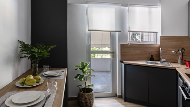 Eine moderne Küche mit Essbereich, einem großen Fenster und einer Tür, die nach draußen führt.