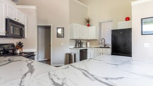 Una cocina moderna con armarios blancos, encimera de mármol y electrodomésticos de acero inoxidable.