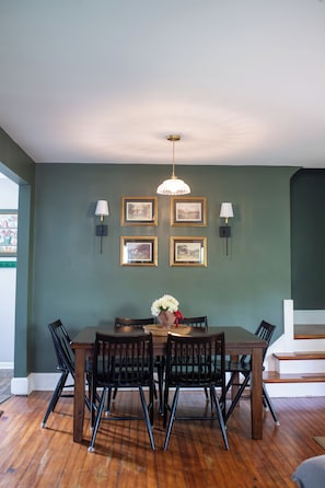 A dining area with a table, chairs, and wall-mounted lamps.