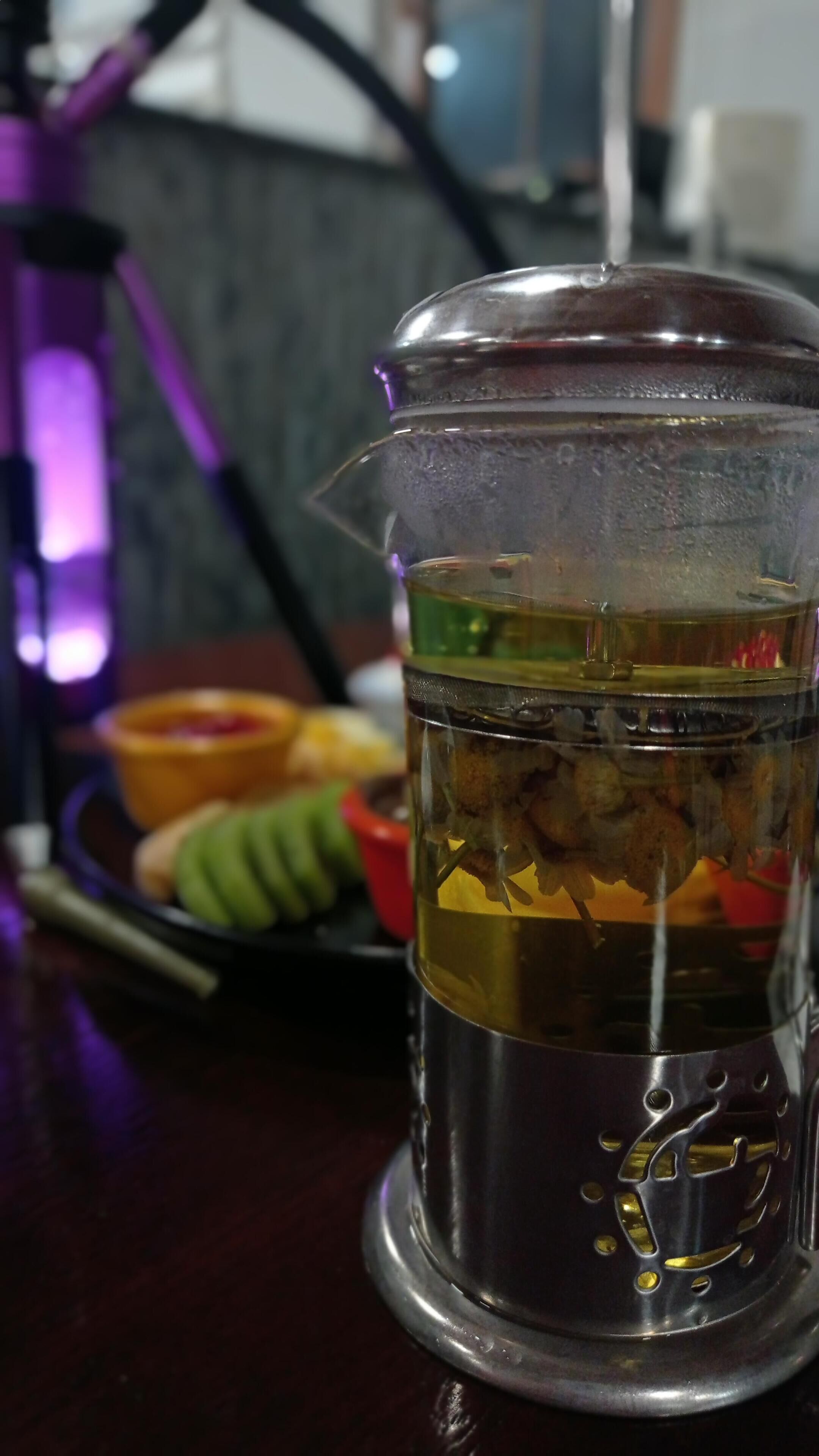 Un recipiente de vidrio transparente con tapa metálica, lleno de un líquido y algunos elementos sólidos, sobre una mesa.