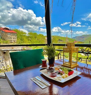 Una mesa dispuesta con comida, una planta en maceta y vistas a un paisaje montañoso.