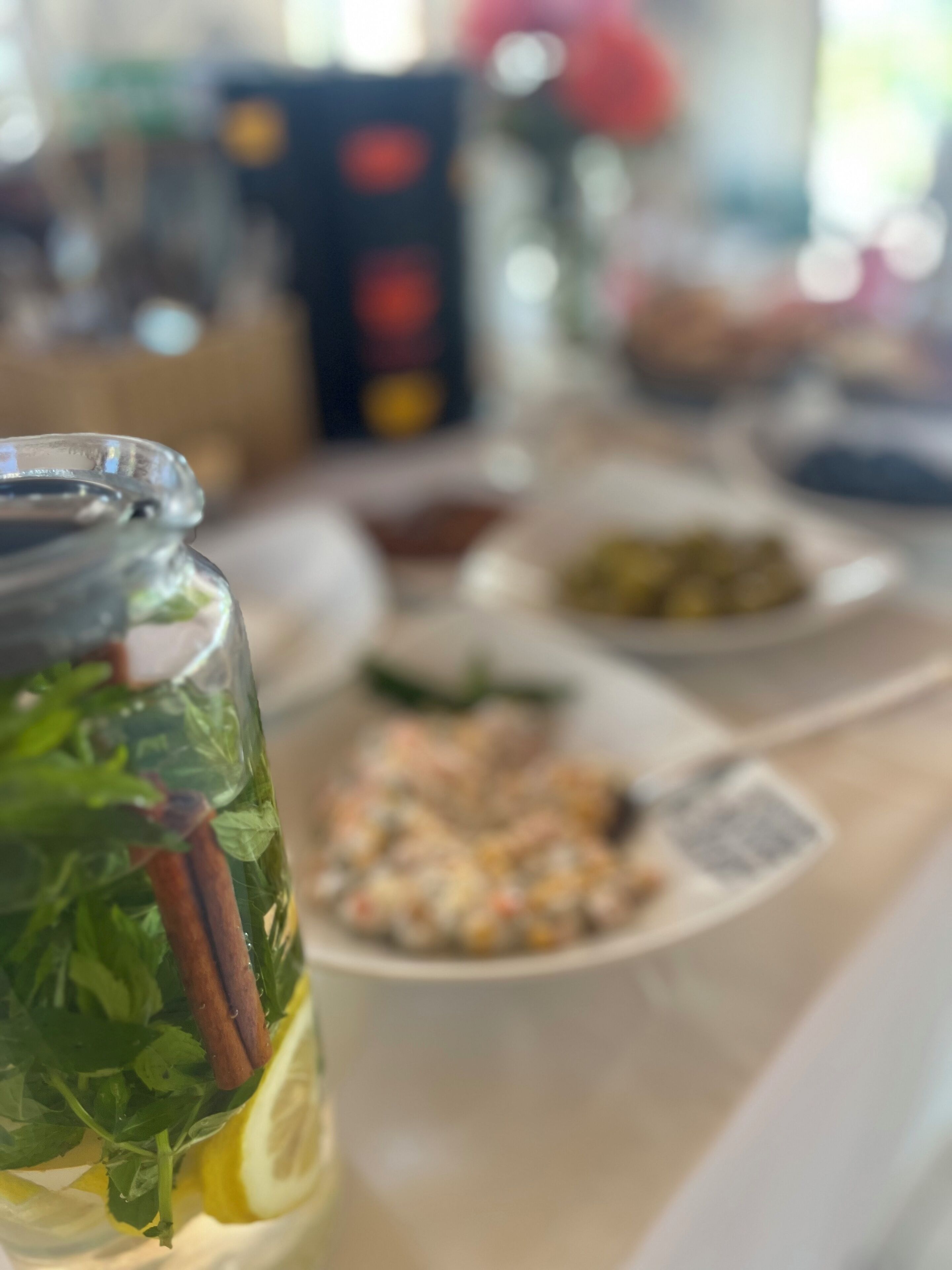 A table with a glass of herbal infusion, a plate of food, and a bowl of olives.