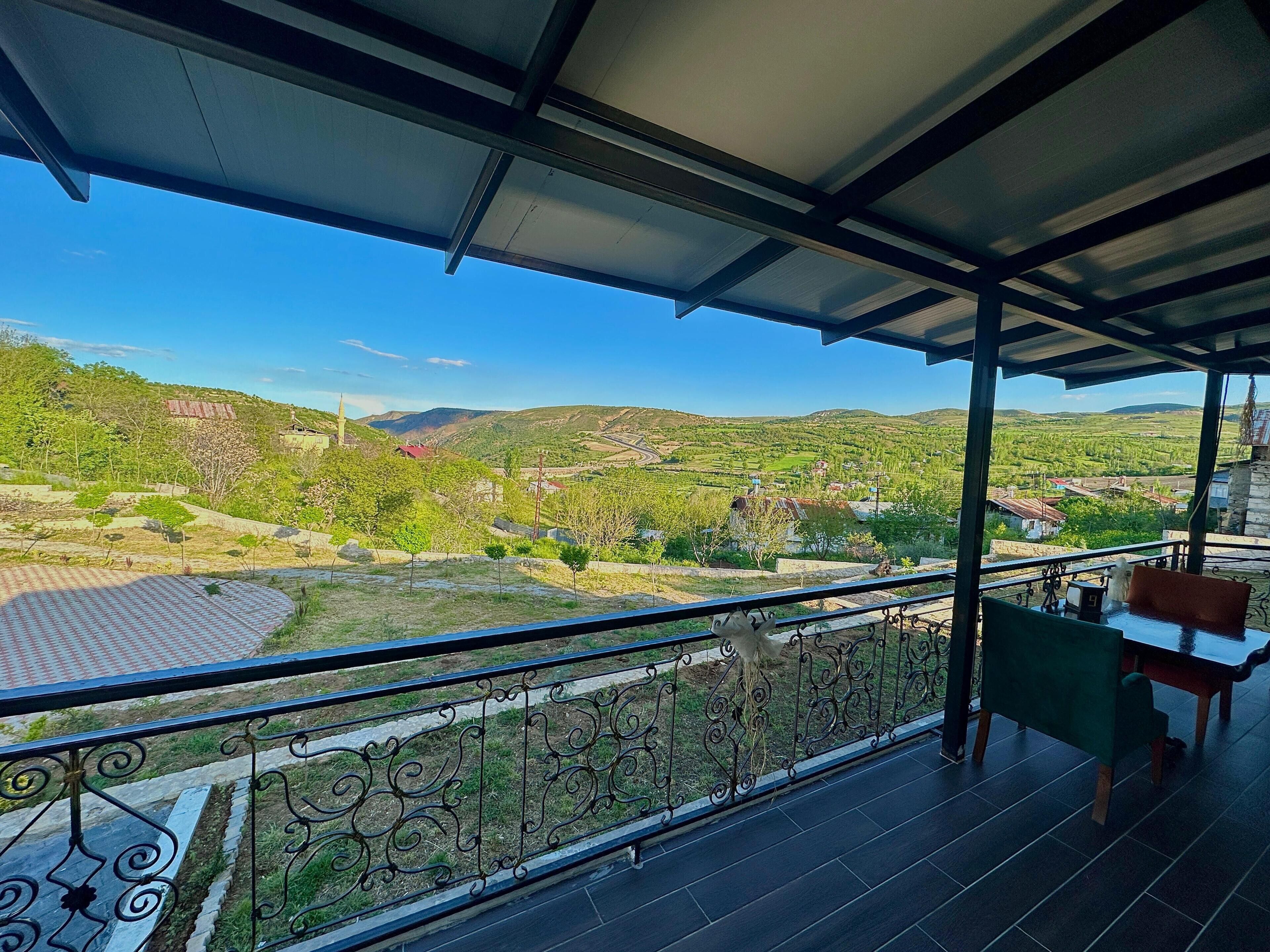 Un balcón con vista a un valle verde y colinas.