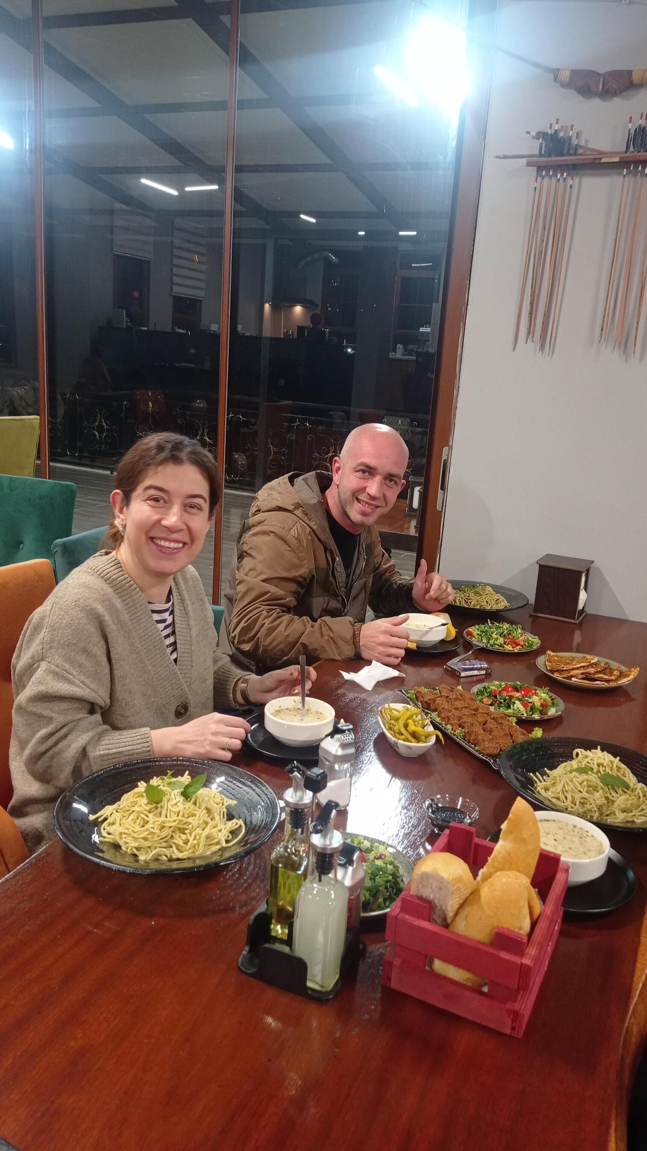 Ein Esstisch mit verschiedenen Speisen, darunter Pasta, Salate und Brot.