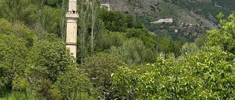 Un paisaje montañoso con una imponente estructura tipo torre en medio de abundante vegetación.