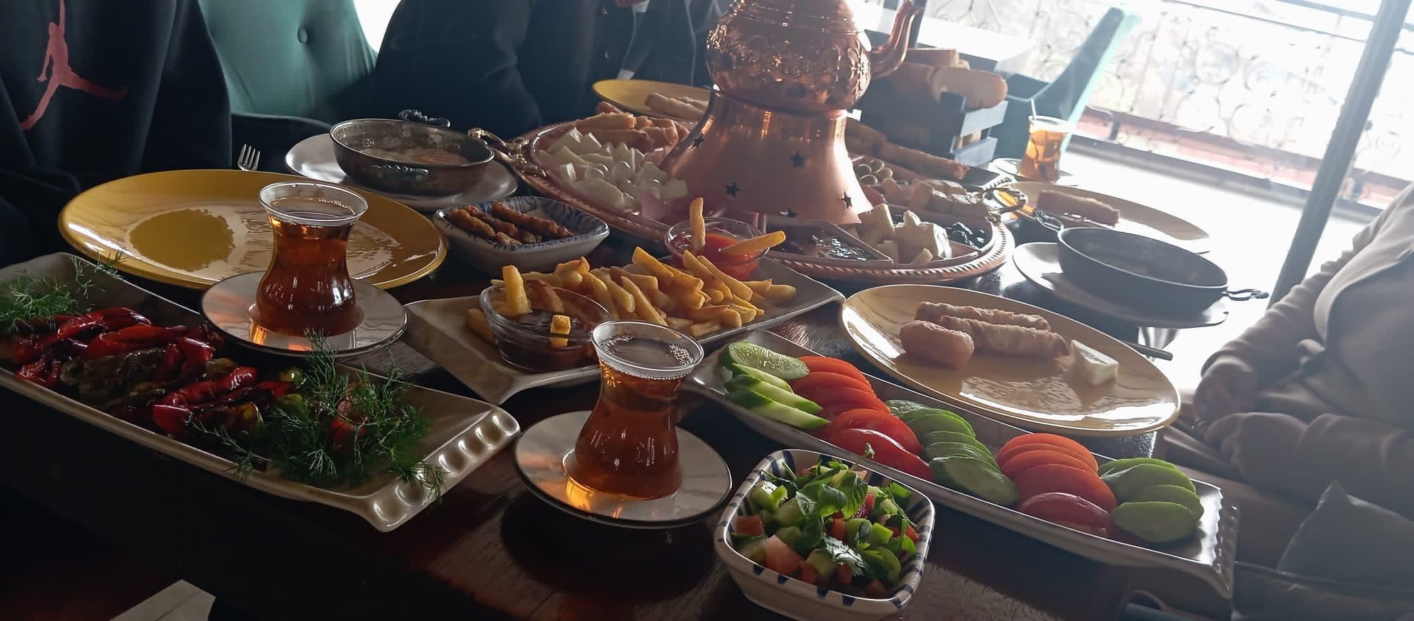 A table with various dishes, including salads, fries, and a pitcher of tea.