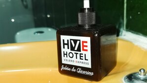 Une bouteille de savon HVE Hotel VELERO EXPRESS sur un lavabo jaune.