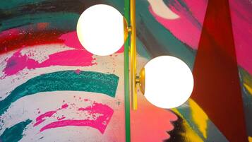 A room with a colorful abstract painting on the wall and two round light fixtures mounted on a vertical pole.